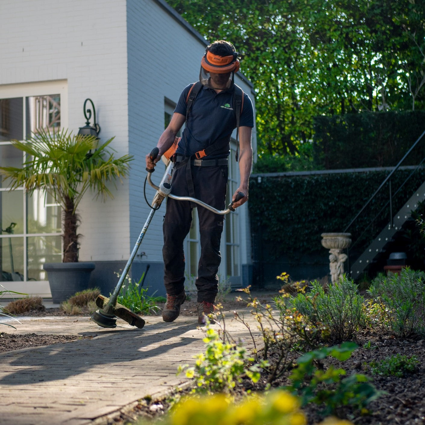 Ein Gartenpfleger reinigt einen Weg durch den Garten