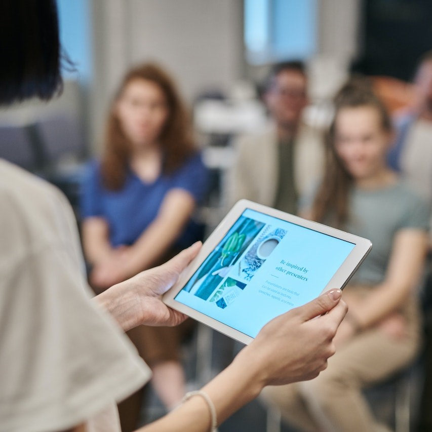 Eine Sprecherin macht einen Seminar-Vortrag und nutzt ihr Tablet zum ablesen