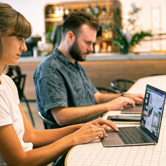 Zwei Menschen arbeiten in einer PR-Agentur an ihren Laptops