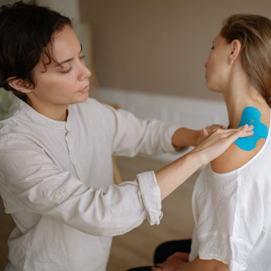 Eine Krankengymnastikerin behandelt die Schulter einer Patientin