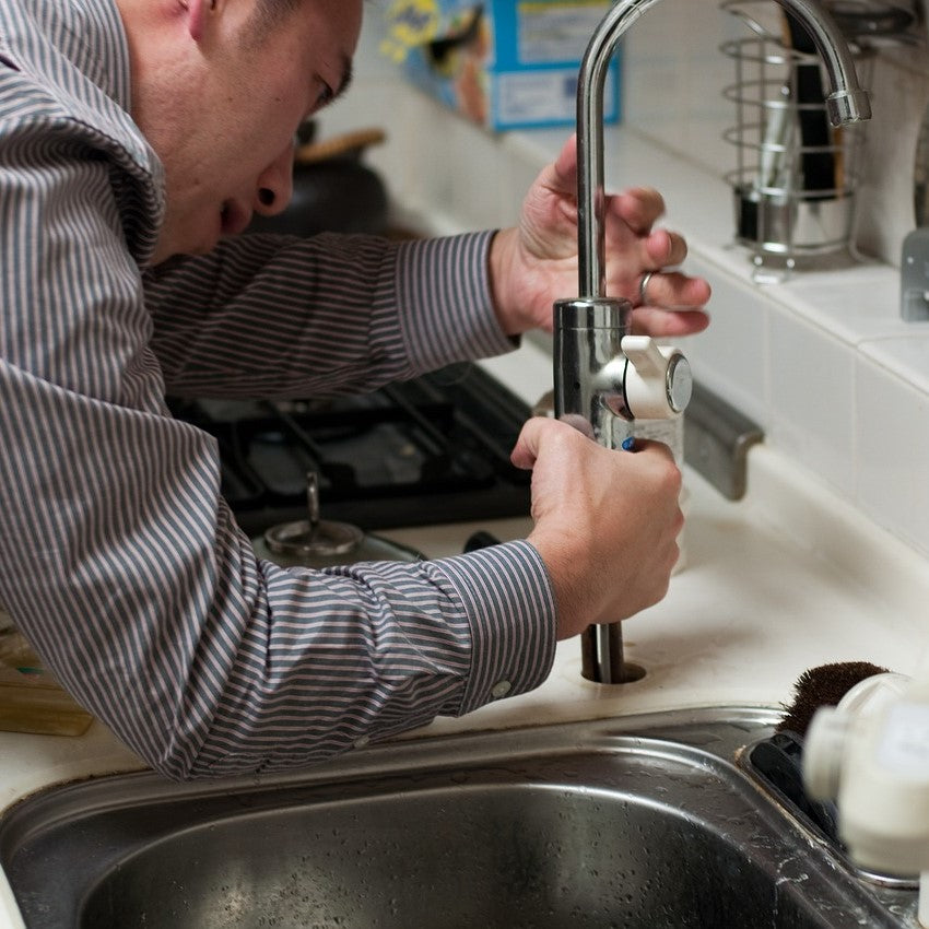 Ein Küchenmonteur arbeitet an einem Wasserhahn