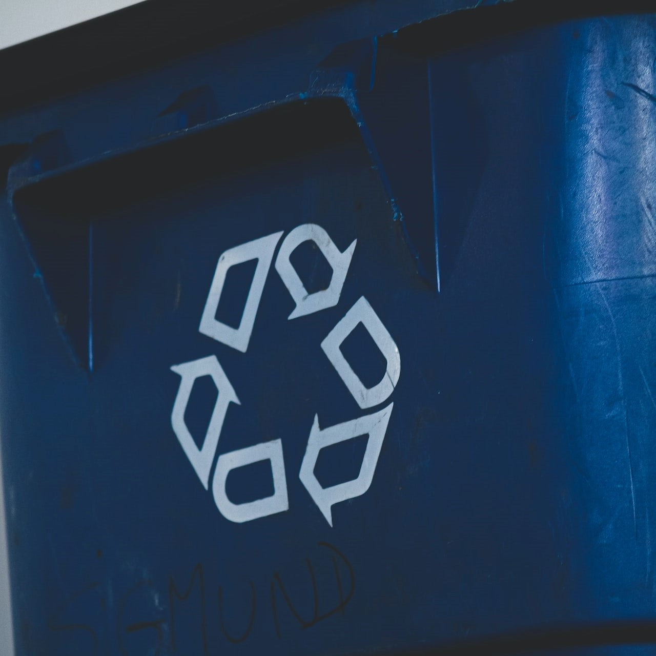 Blaue Mülltonne mit einem weißen Recycling-Zeichen