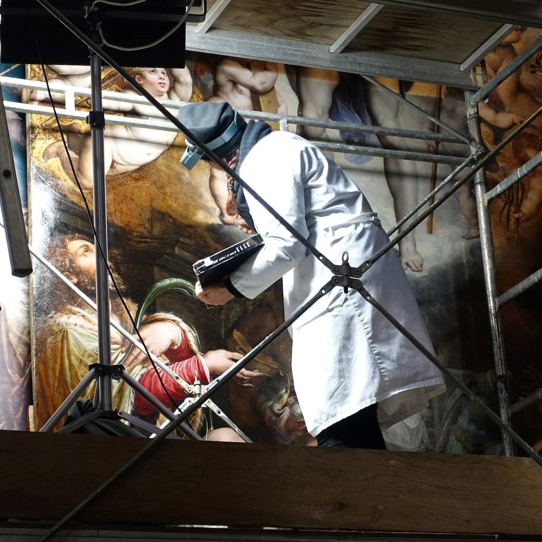 Eine Restauratorin arbeitet an einem alten Gemälde
