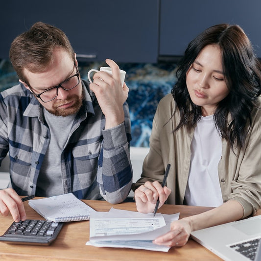 Ein Mann und eine Frau machen eine Rechnung mit Papier und Taschenrechner