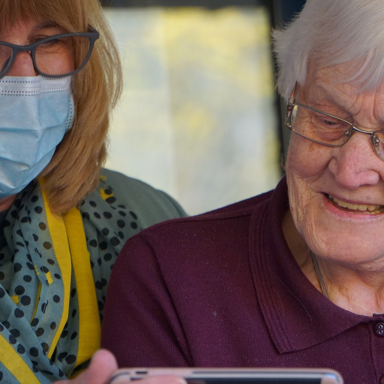 Eine Frau zeigt einer älteren Frau etwas auf einem Smartphone