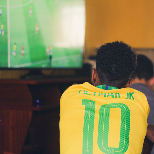 Ein Fussballfan mit Neymar-Trikot sitzt in einer Sportsbar und schaut auf einen Fernseher