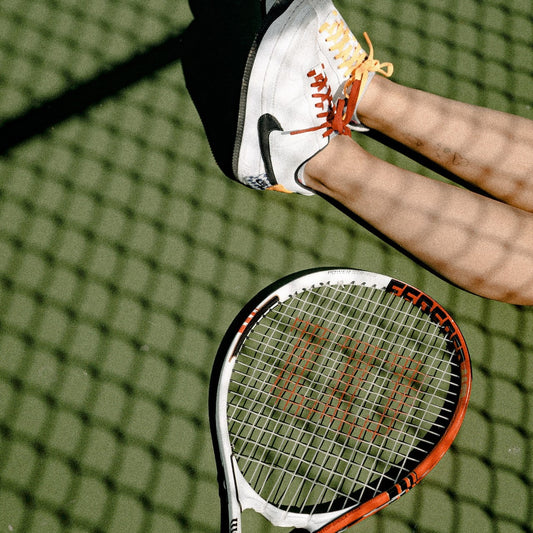 Ein Tennisspieler sitzt auf dem Rasen